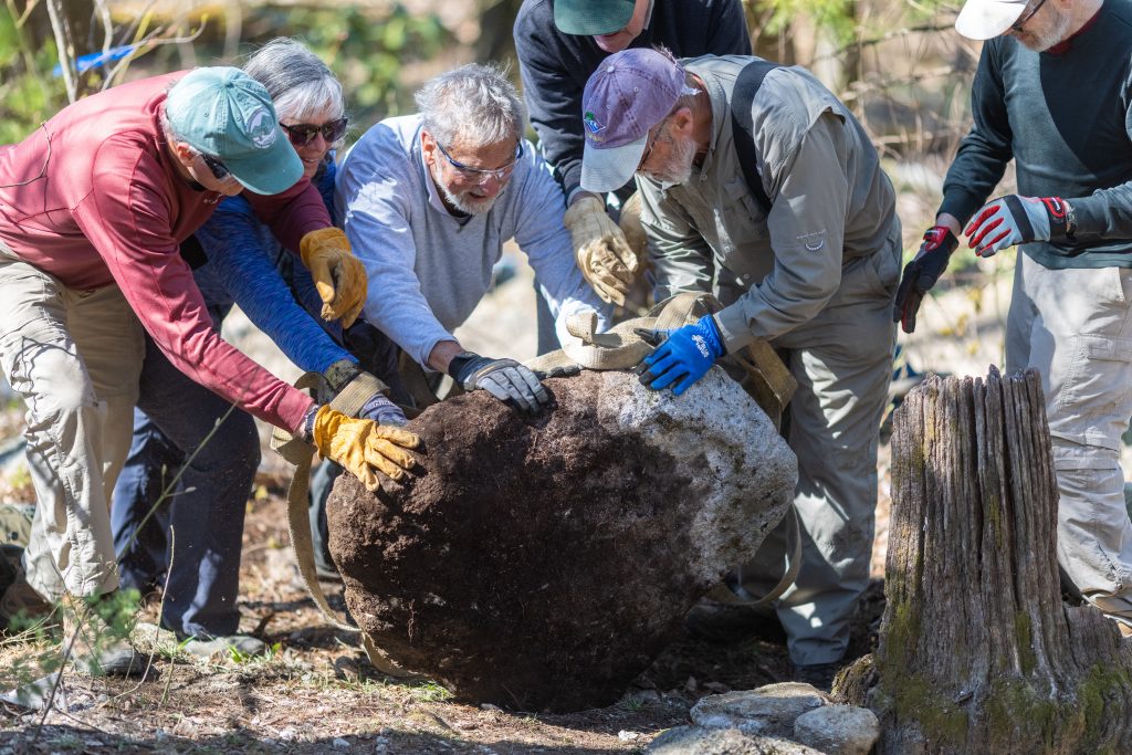 Trail volunteers working together to move a large boulder