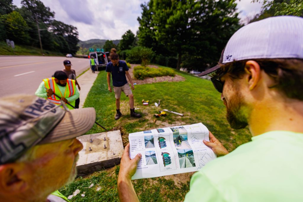 a man is studying an installation guide for the Watauga County wayfinding signage