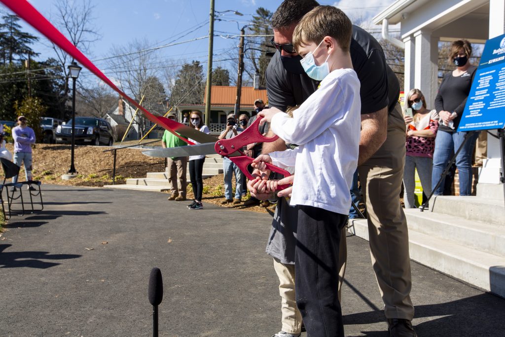 a young boy and his father cut the ribbon to open a new construction project.