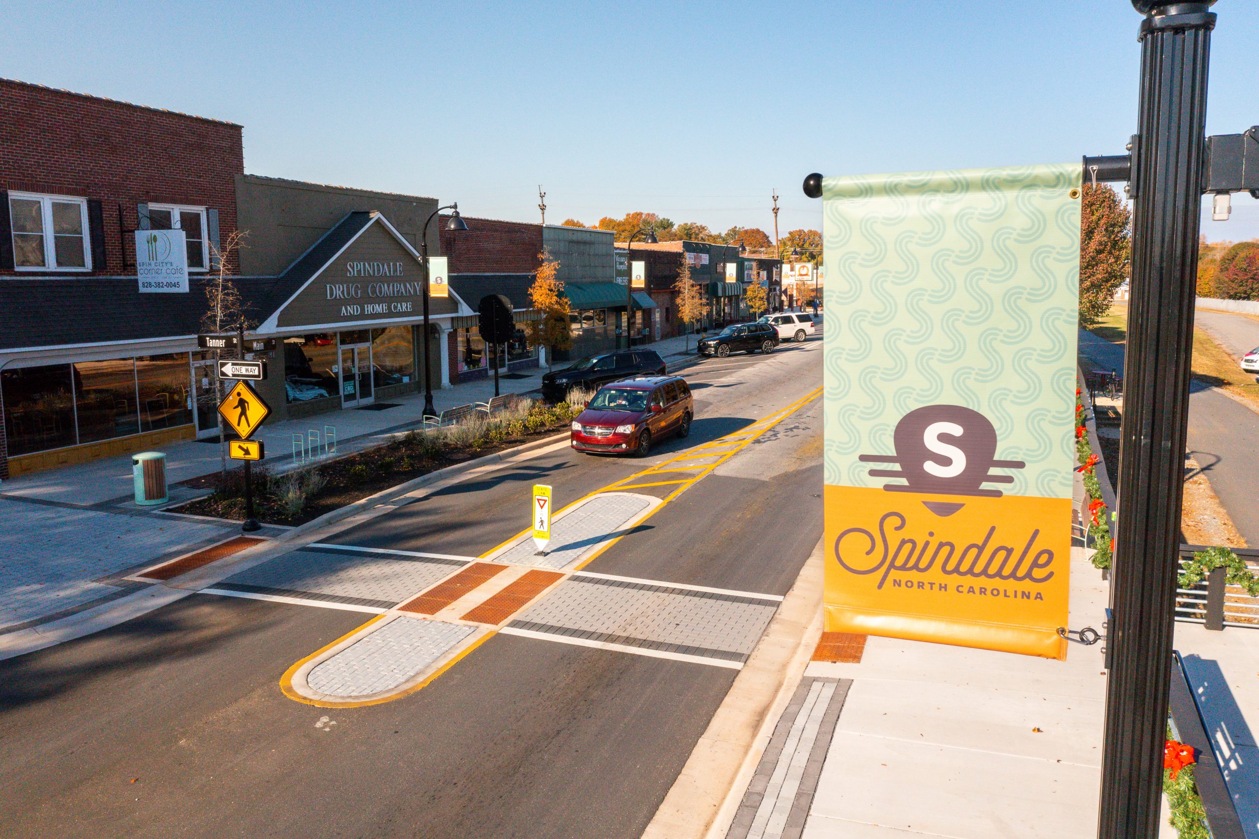 A yellow and green banner featuring the Spindale brand flies above the newly widened street in Spindale